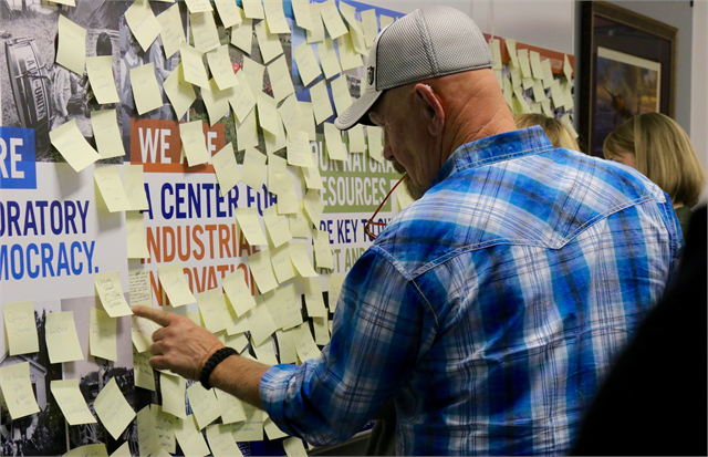A man examines a wall of sticky notes.