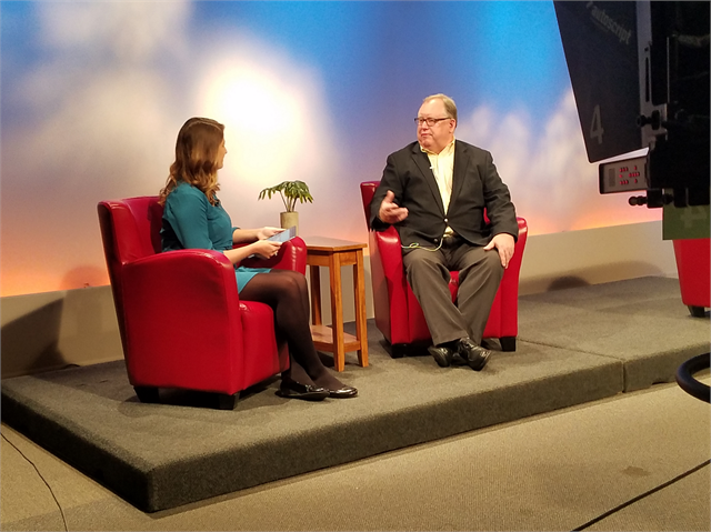 Two people on a studio stage chatting.