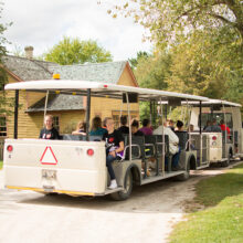 People sitting on a white tram on a gravel road